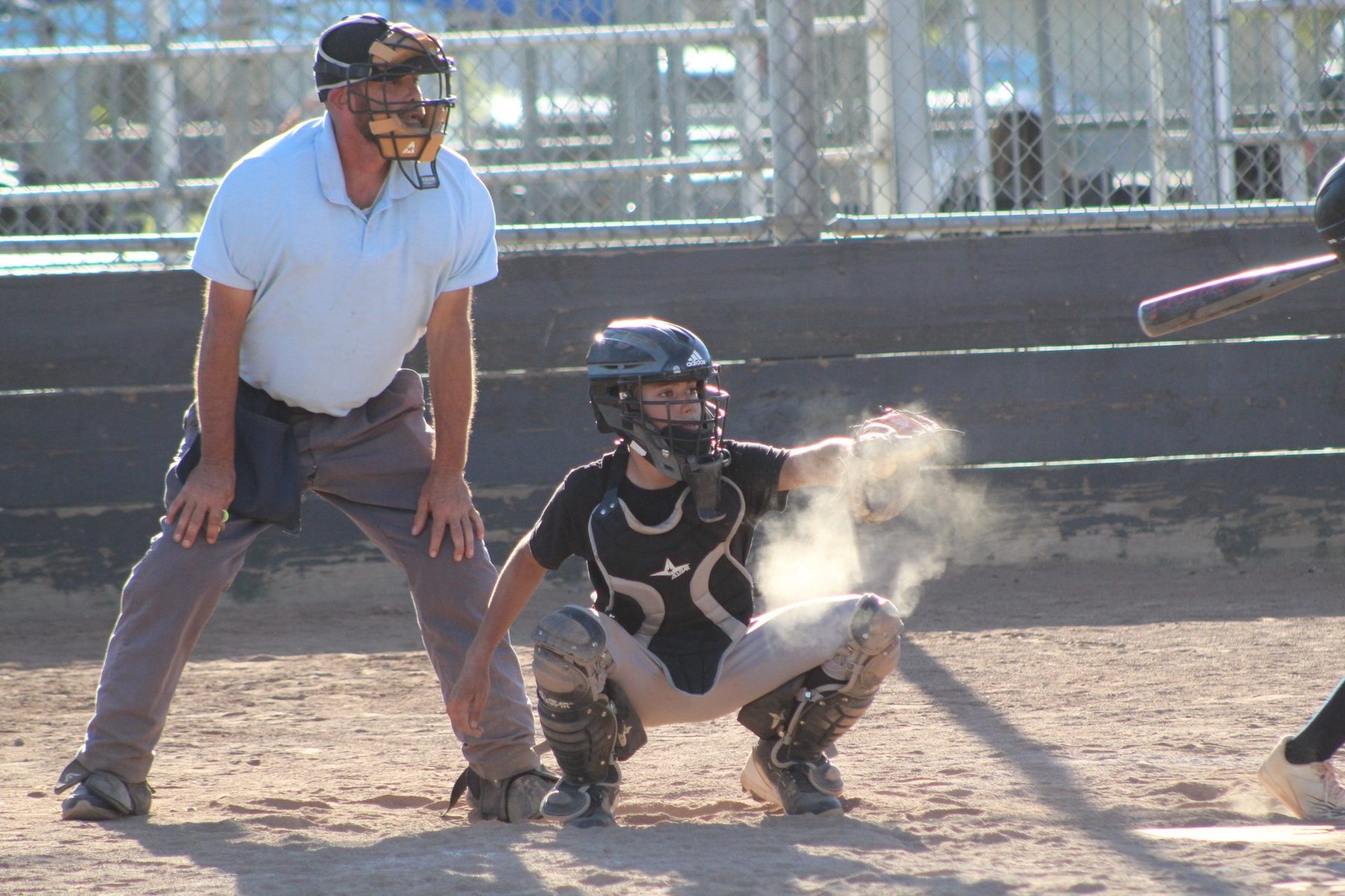 Luke Sevilla catching a pitch as dust rises